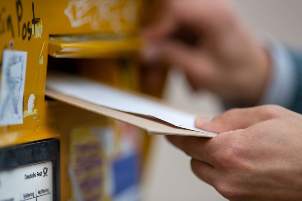 Wird Porto für Briefe bald noch teurer? Ein Mann wirft Briefe in einen Briefkasten (Symbolbild).