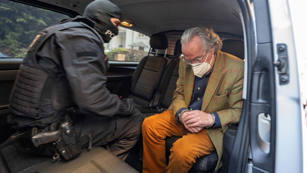 Bei einer Razzia gegen sogenannte «Reichsbürger» sitzt ein vermummter Polizist, nach der Durchsuchung eines Hauses, mit dem festgenommenen Heinrich XIII Prinz Reuß (r) in einem Polizeifahrzeug. 