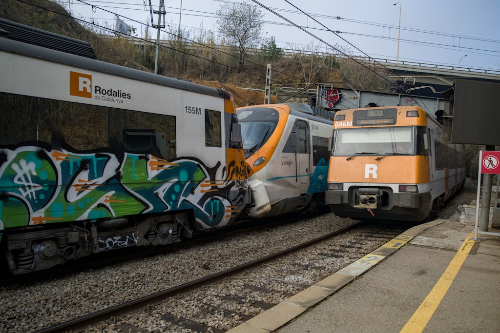 Ein Zug fährt neben zwei Zügen, die im Bahnhof Montcada i Reixac zusammengestoßen sind. 