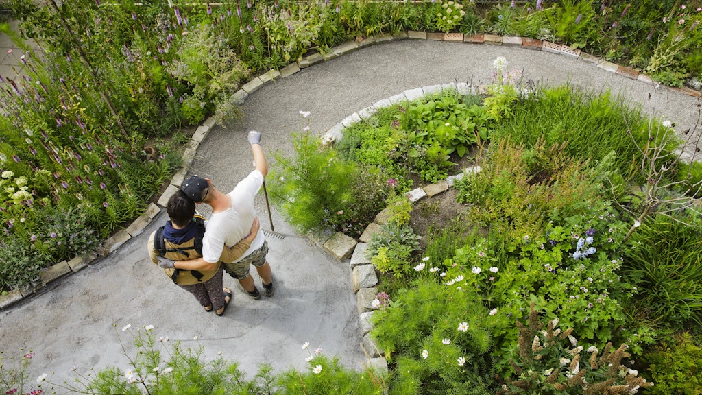  Ein junges Paar steht vor einem neu angelegten Weg in seinem Schrebergarten. 