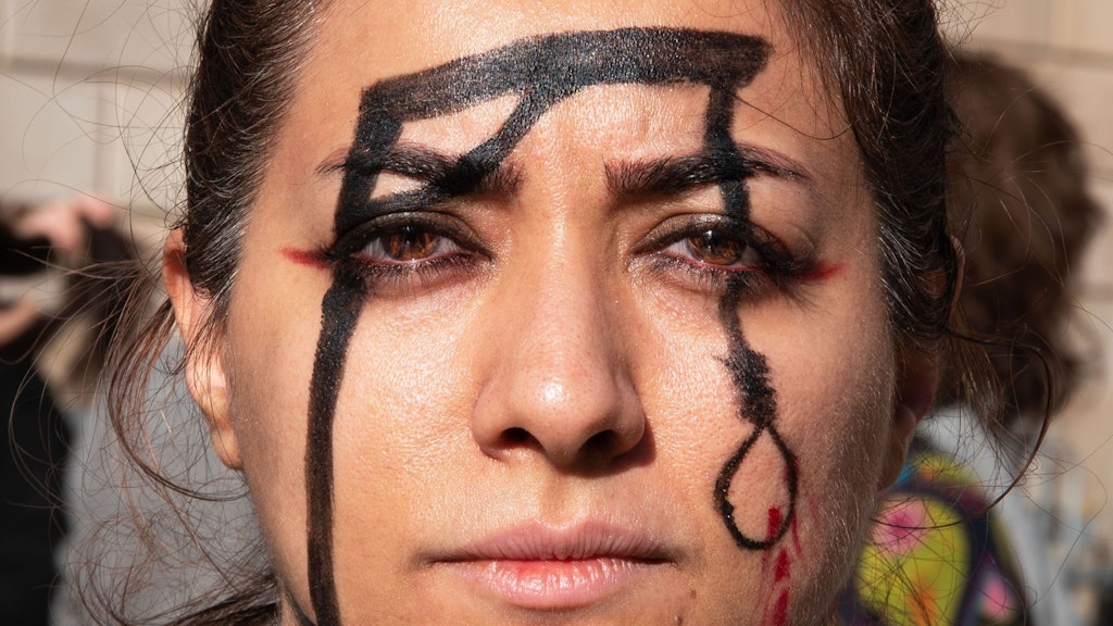 Eine Frau hat einen Galgen auf ihr Gesicht gemalt, um während der Demonstration an die Ermordung von Mohsen Shekari zu erinnern.