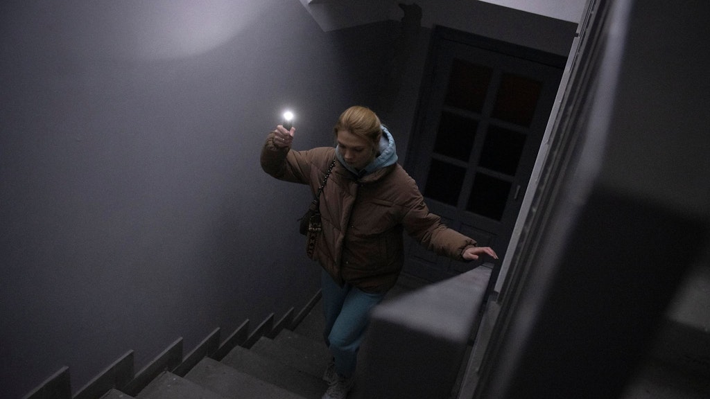 Kein Strom, kein Aufzug: Anastasia Pyrozhenko steigt in Kiew die Treppe zu ihrer Wohnung hinauf, eine Lampe in der Hand. 