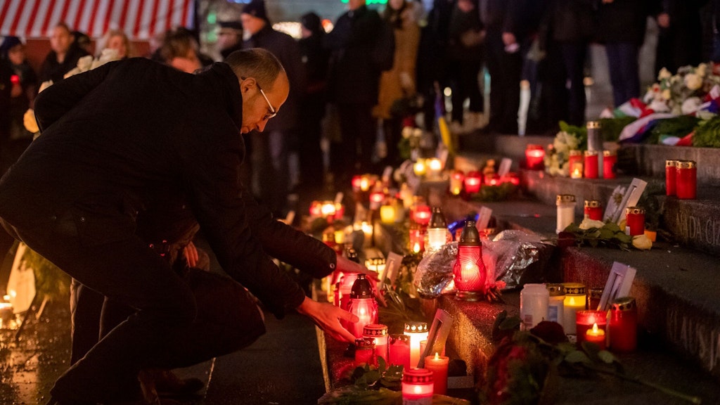 Menschen zünden bei der Gedenkveranstaltung zum Terroranschlag auf dem Berliner Breitscheidplatz an der Gedächtniskirche Kerzen an. 