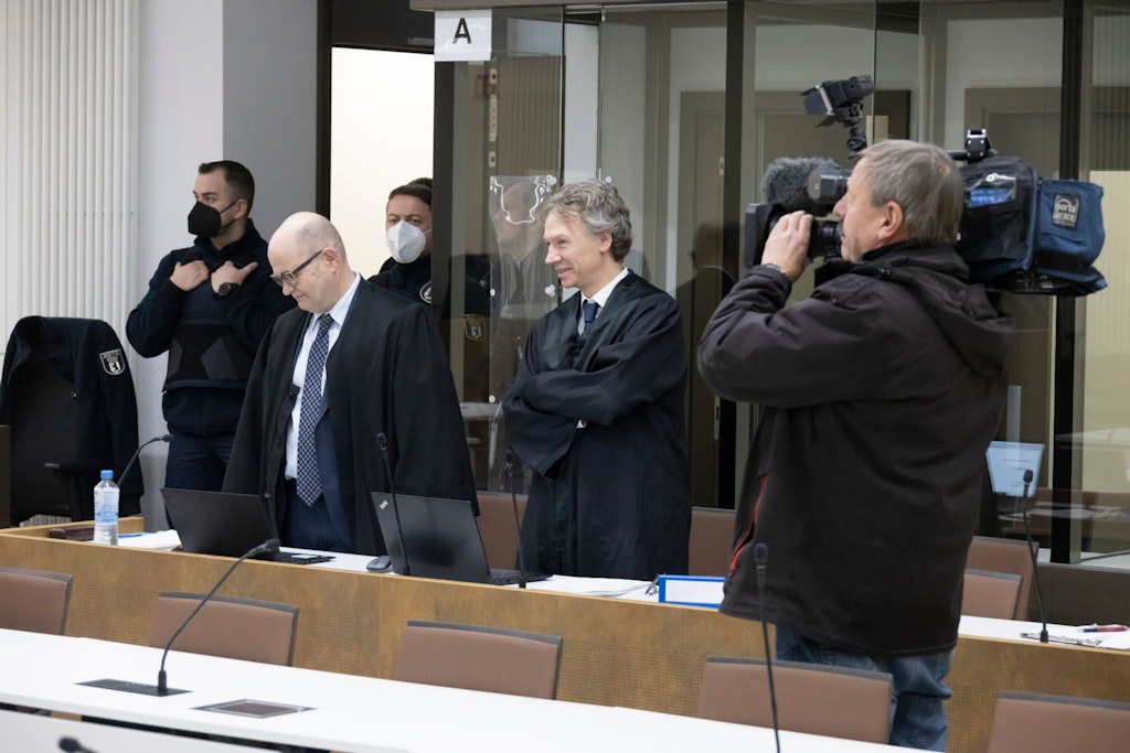 Der Angeklagte sitzt hinter Panzerglas, Richter, Staatsanwalt und Schöffen stehen unter Polizeischutz.