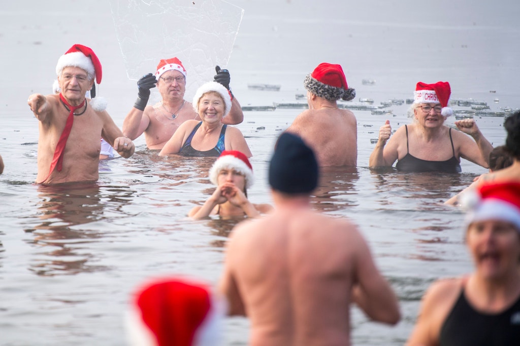 Mitglieder des Vereins Berliner Seehunde baden beim traditionellen Weihnachtsbaden im Orankesee zwischen Eisschollen.