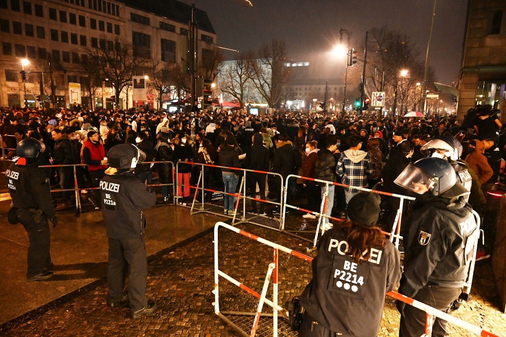 Silvesternacht 2021: Obwohl die große Silvesterparty am Brandenburger Tor erneut ausfiel, drängen viele Leute zum Pariser Platz. Die Polizei kontrolliert hinter einer Absperrung.