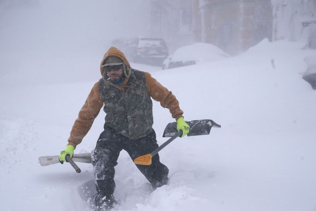 Travis Sanchez stapft mit zwei Schaufeln durch den Schnee in Buffalo, um einem gestrandeten Autofahrer zu helfen.