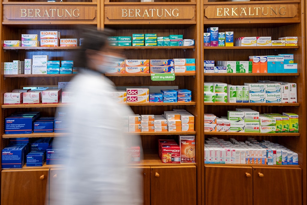 Eine Mitarbeiterin geht in der Schlachtensee-Apotheke an einem Regal mit Medikamenten vorbei.