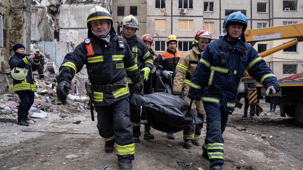 Feuerwehrleute tragen in Dnipro einen weiteren Leichnam weg, den sie in den Trümmern gefunden hatten.