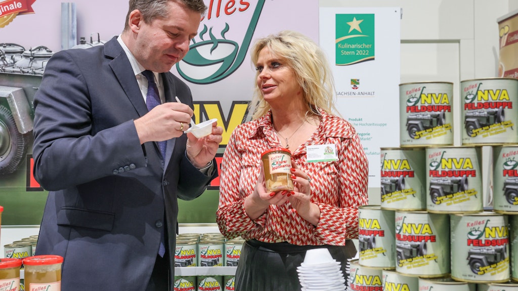 Sachsen-Anhalts Landwirtschaftsminister Sven Schulze schaut bei der Grünen Woche am Stand von Antje Mandelkow vorbei, kostet die NVA-Suppe. Sein Bundesland zeichnete vergangenes Jahr das Gericht mit dem Kulinarischen Stern aus.