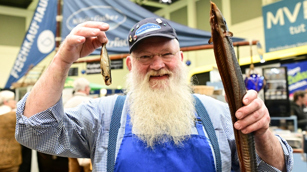 Ein Müritz-Fischer mit traditionellem Aal und Sprotte auf der Grünen Woche- paar Hallen weiter zeigen Sachsen, wie man aus Fisch Wurst und Burger macht.