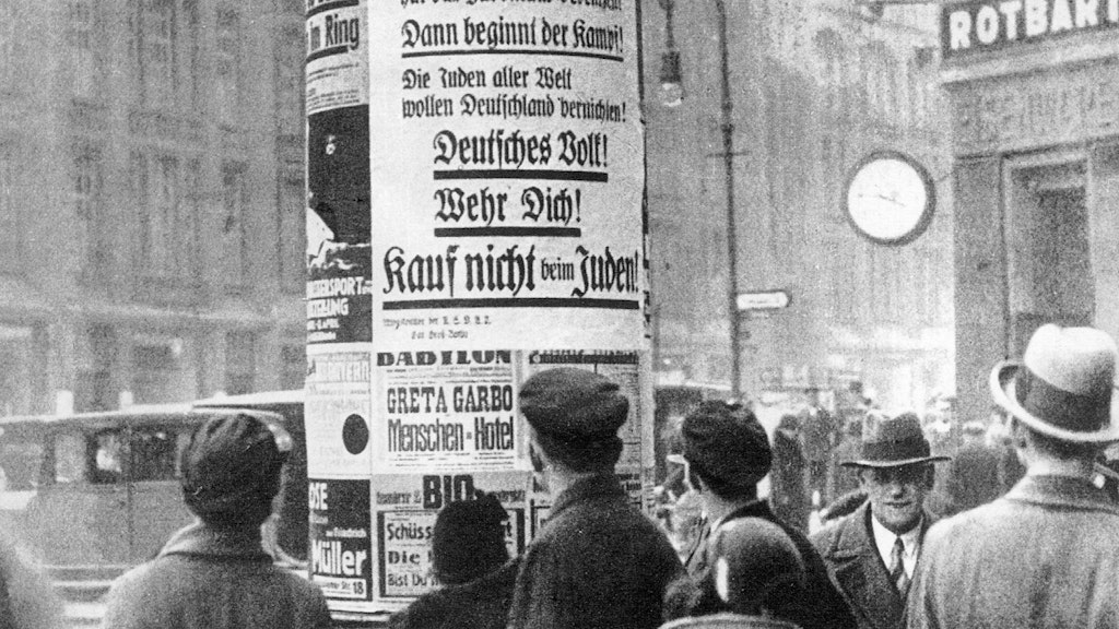 1. April 1933: Berliner lesen an einer Litfaßsäule den Boykottaufruf der jüdischen Geschäfte. Darunter ist ein Filmplakat von „Menschen im Hotel“ mit Greta Garbo.