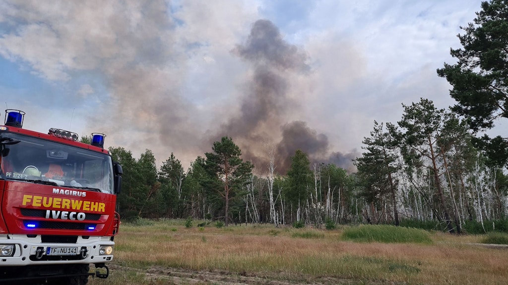Ein Einsatzfahrzeug der Feuerwehr stehtim Sommer 2022 in der Nähe des brennenden Waldstücks bei Jüterbog. Foto: Julian Stähle/dpa-Zentralbild/dpa