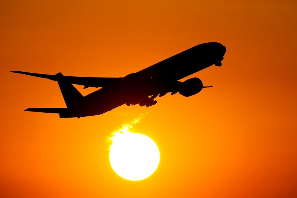 Ein Flugzeug startet in den Sonnenuntergang.