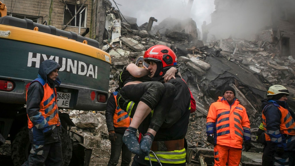 Ein Feuerwehrmann trägt eine Frau, die aus den Trümmern des Hauses in Dnipro gerettet worden war.