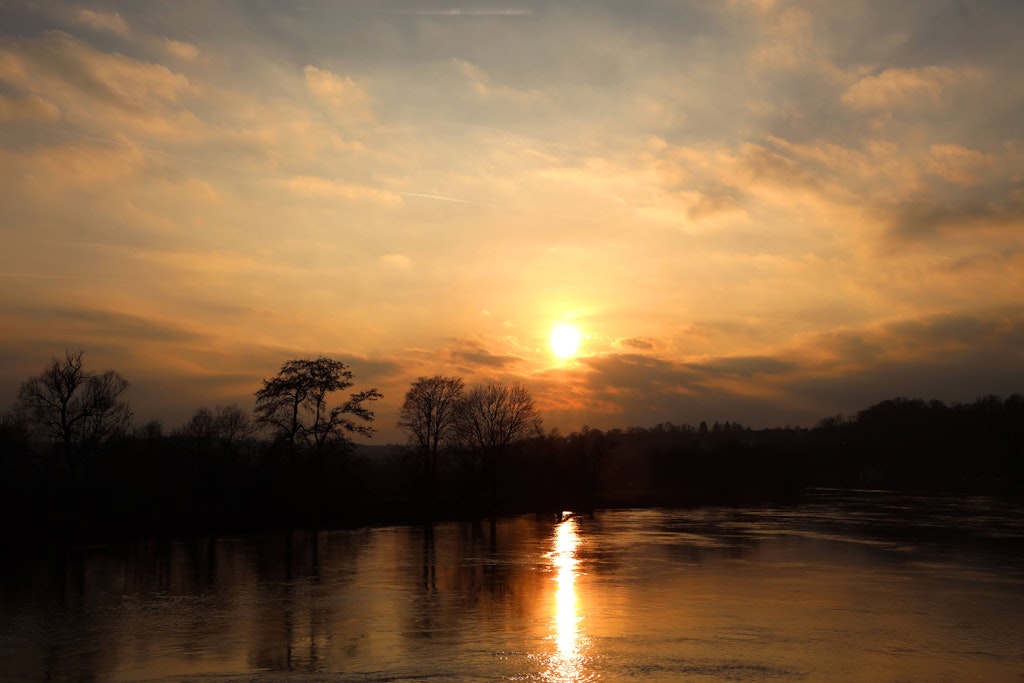 Die Sonne geht über einem See unter. Der Winter wird derzeit recht frühlingshaft in Deutschland.