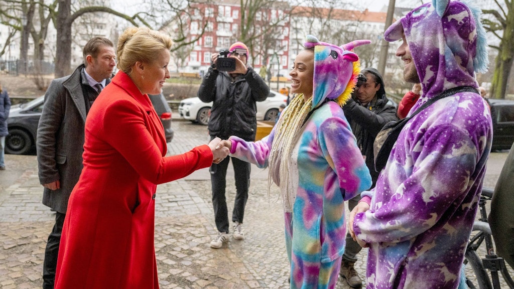 Franziska Giffey (SPD), Regierende Bürgermeisterin von Berlin und Spitzenkandidatin der Berliner SPD, begrüßt vor ihrem Wahllokal in Friedrichshain zwei Wähler in Einhorn-Kostümen. 