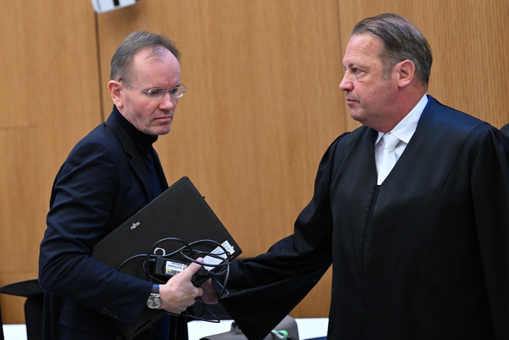 Mit dem Laptop unter dem Arm geht Markus Braun im Gerichtssaal an seinem Anwalt Alfred Dierlamm vorbei.