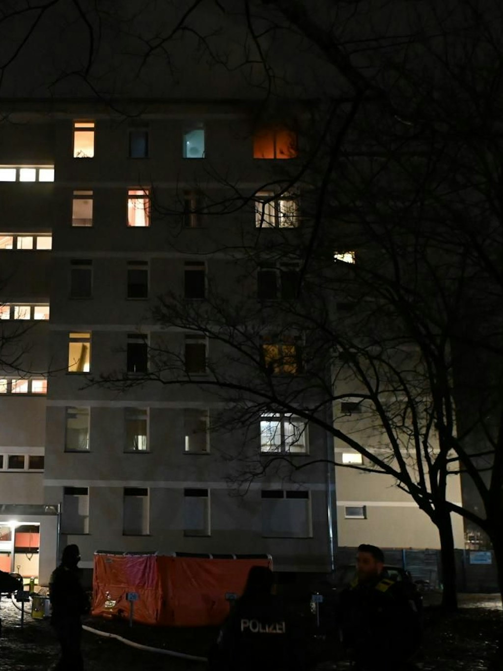 Ganz oben im Haus ist roter Feuerschein hinter einem Fenster zu sehen.