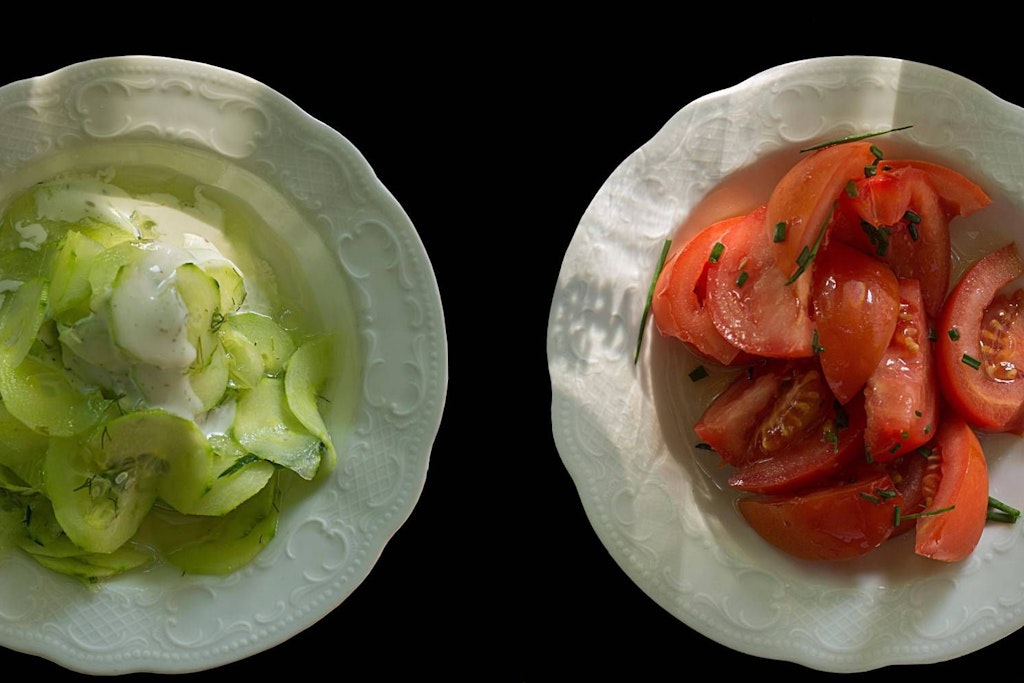 Ein Teller mit Gurkensalat und einer mit Tomatensalat.