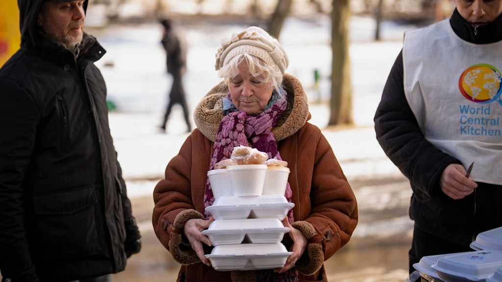 Eine Frau aus Charkiw trägt eine warme Mahlzeit, die sie von einer humanitären Organisation erhalten hat. 