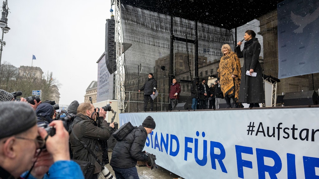 Sahra Wagenknecht spricht, während Alice Schwarzer auf der Bühne der Kundgebung neben ihr steht.