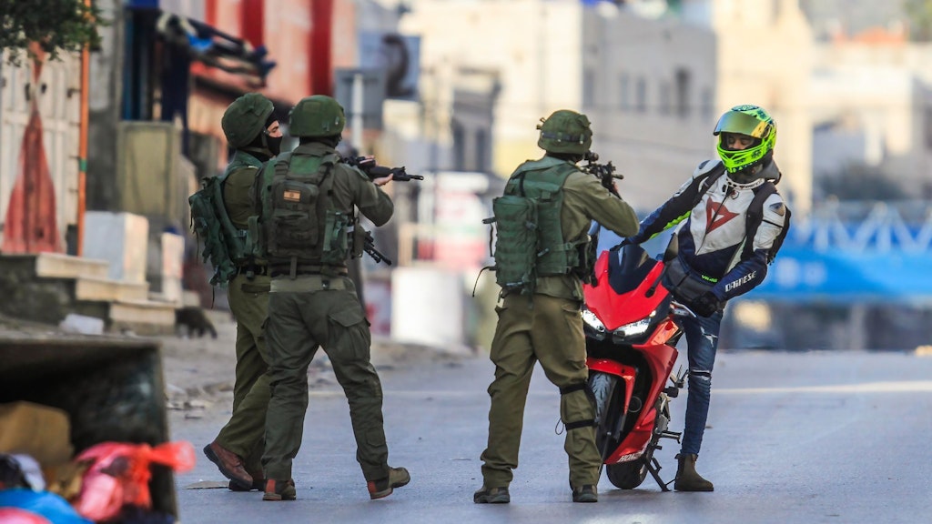 Mit vorgehaltenen Waffen halten israelische Soldaten in Nablus einen palästinensischen Motorradfahrer an.
