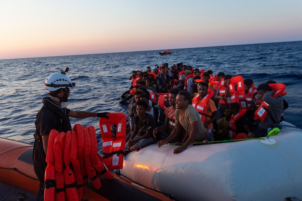 Ein Seenotretter vom deutschen Schiff „Sea-Watch 3“ verteilt Rettungswesten an Menschen in einem Schlauchboot. Wird es auch künftig solche Einsätze noch geben können?