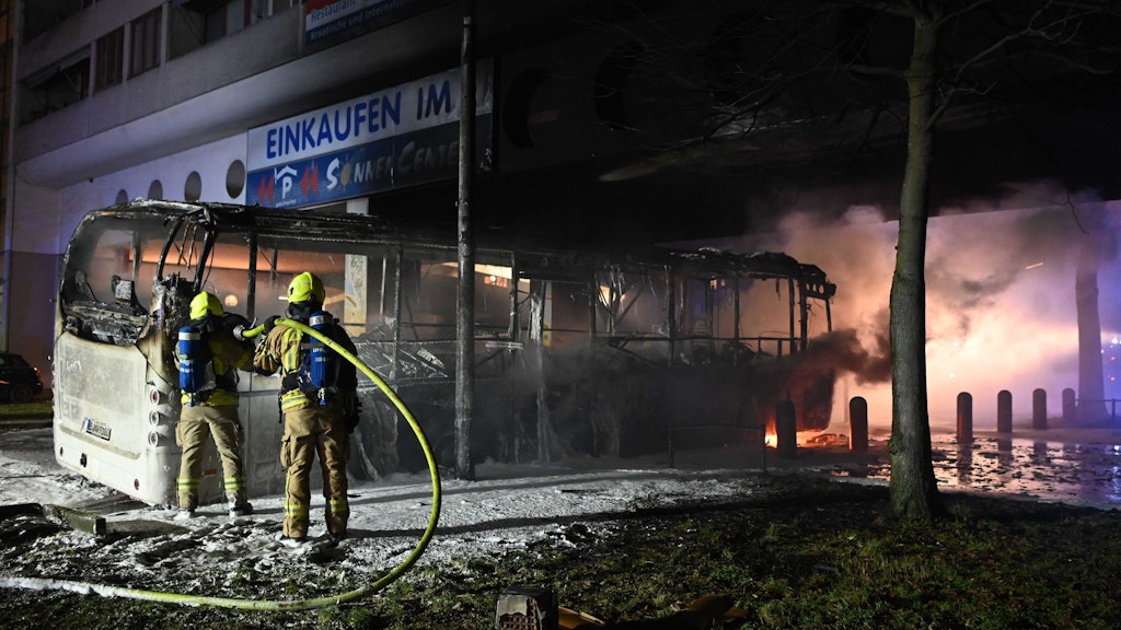 Einsatzkräfte der Feuerwehr löschen in der Silvesternacht an der Sonnenallee im Bezirk Neukölln einen brennenden Bus, der von Unbekannten angezündet worden war.