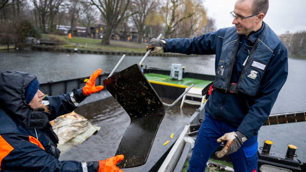 Andreas Müller (r) und Stephan Strauch, Mitarbeiter vom Wasser- und Schifffahrtsamt, verladen bei einer Schiffsfahrt zur Hindernisbergung im Landwehrkanal einen aus dem Wasser geholten Stuhl auf einen schwimmenden Container. 