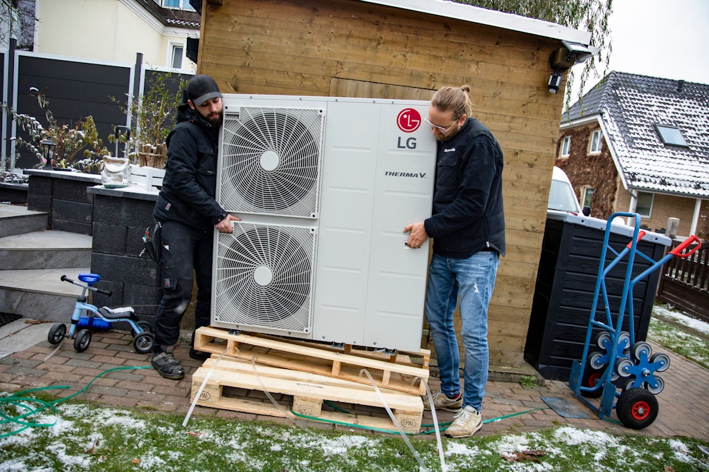 Monteure beim Einbau einer Wärmepumpe an einem Wohnhaus – Experten zur Installation sind auf absehbare Zeit knapp.