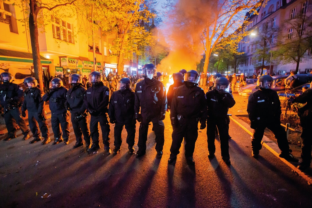 Barrikaden brannten: Polizisten stehen am 1. Mai 2021 vor einem Feuer auf der Straße am Rande der Demonstration linker und linksradikaler Gruppen.