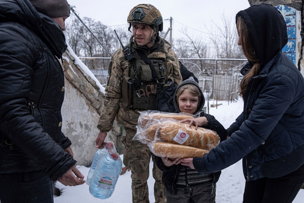 Ein ukrainischer Polizist der Weißen Engel verteilt Hilfsgüter an eine Familie. Die Spezialeinheit riskiert ihr Leben, um in Dörfer und Städte an der Front zu gehen.