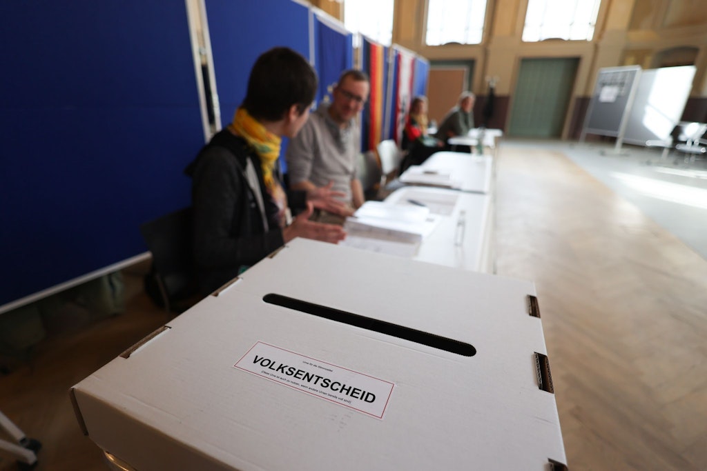 Klima-Volksentscheid in Berlin: Wahlhelfer sitzen vor einer Wahlurne in einem Wahllokal in Weissensee. 