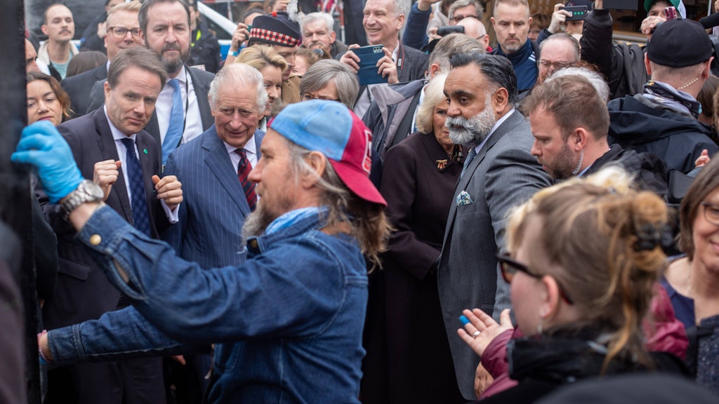 Ein Händler öffnet seinen Räucherofen, zeigt Charles frischen geräucherten Aal. Camilla scheint davon offensichtlich nicht begeistert zu sein.