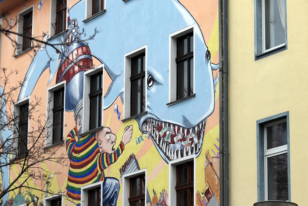 Ein Immobilien-Hai auf einer Häuserfassade – auch gierige Wohnungseigentümer treiben die Mietpreise hoch.