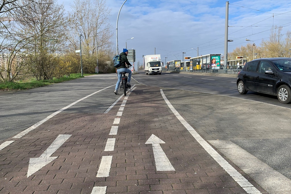 Carsten Borholter kann angesichts des Pfeils, der Radfahrer in den Gegenverkehr auf der Falkenberger Brücke schickt, nur Verwunderung äußern. Wenn er neben der Haltestellen-Bucht auf den Gehweg ausweicht, kommt er Fußgängern ins Gehege.