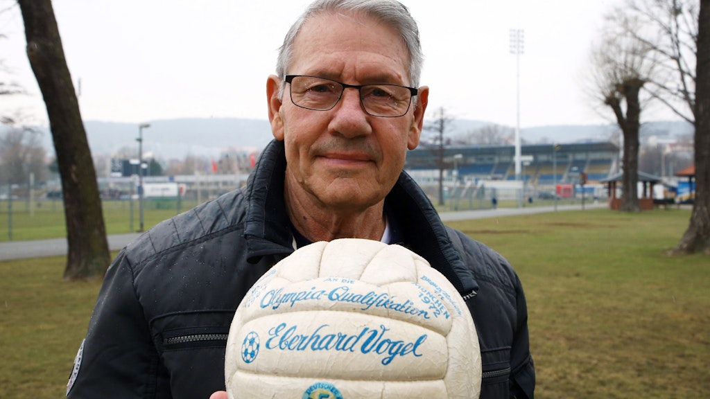 Ein Foto aus dem März 2018: Eberhard Vogel steht mit dem Originalball der Olympiaqualifikation von 1972 auf dem Gelände des Ernst-Abbe-Sportplatzes in Jena.