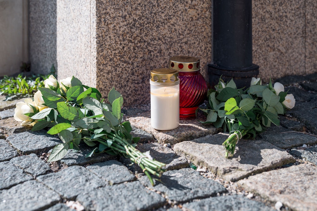 An der Straßenecke zur Zufahrtsstraße zum Kinder- und Jugendhilfezentrum, in dem eine Zehnjährige tot aufgefunden wurde, liegen Blumen und Grablichter auf dem Gehweg.