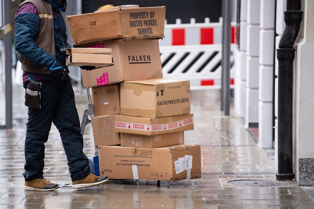 Ein Paketbote liefert in der Innenstadt seine Pakete aus.