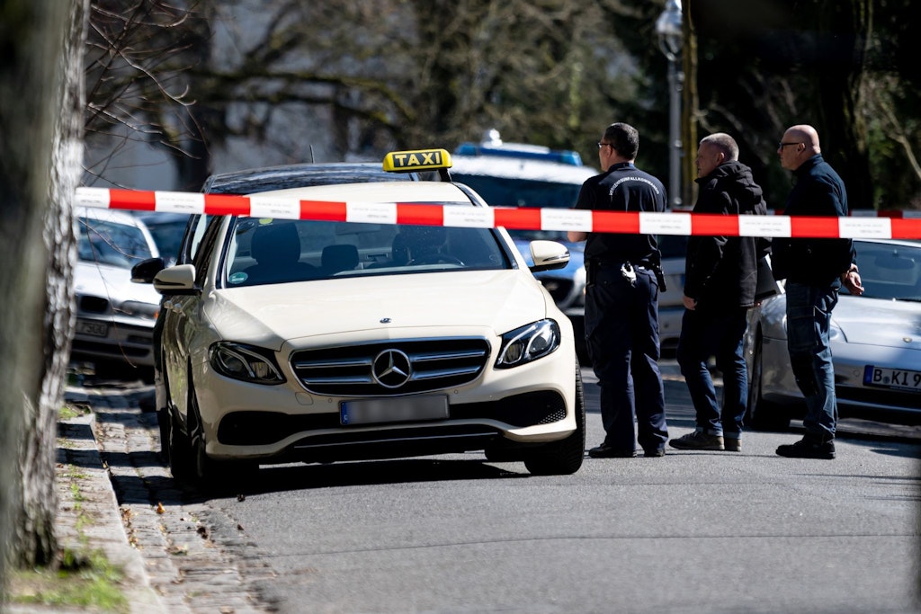 Mitarbeiter der Berliner Polizei stehen vor dem Taxi des ermordeten Fahrers in Berlin-Grunewald. 