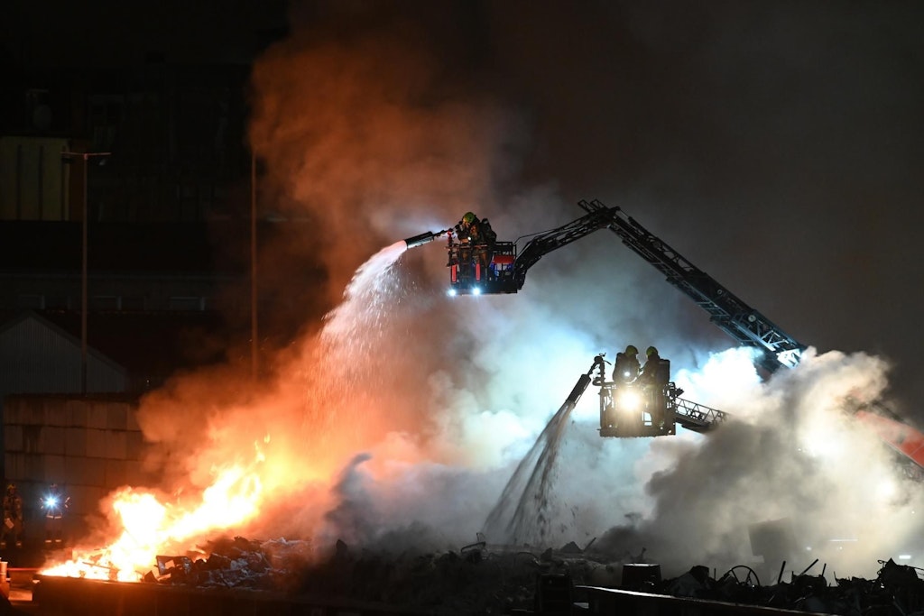 Über Drehleitern versuchen Feuerwehrleute, die Flammen auf dem Schrottkahn im Neuköllner Schifffahrtskanal zu löschen.