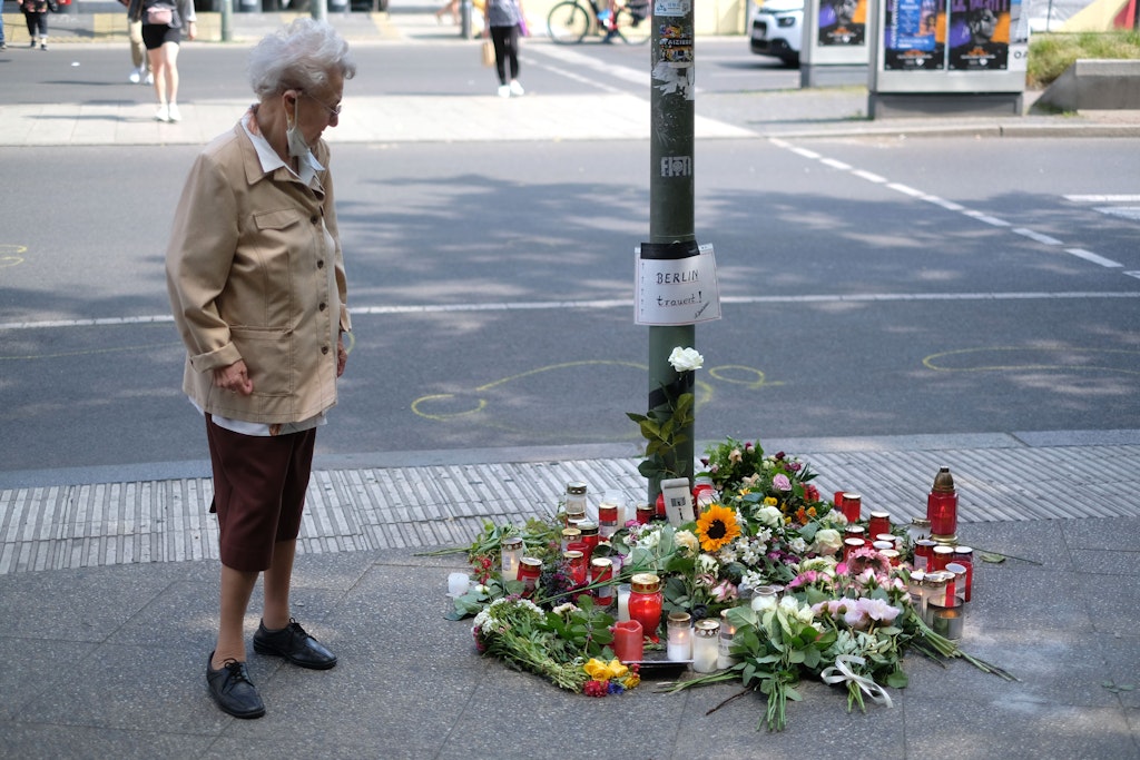 Eine Passantin geht an der Unglücksstelle vorüber. Menschen haben am Kudamm Blumen abgelegt. 