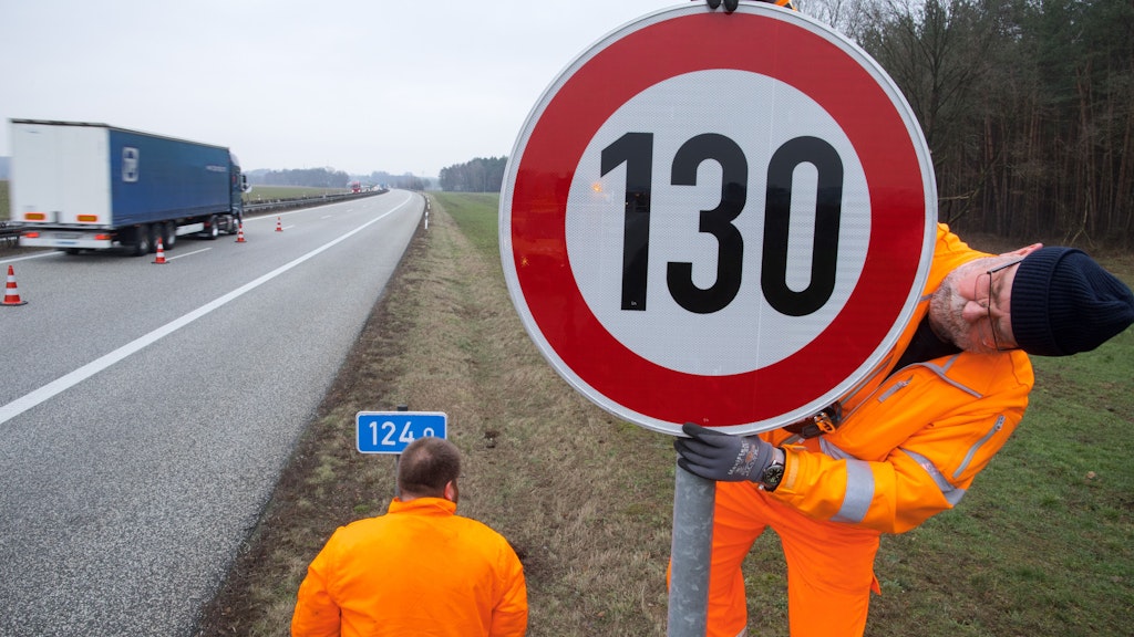 Ein Straßenwärter montiert an der Autobahn A24 ein Tempolimit-Schild. 