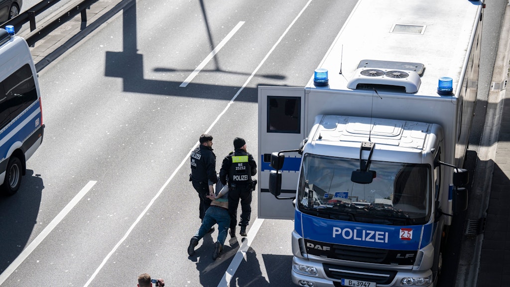 Zwei Polizisten tragen einen Aktivisten zum Gefangenentransport auf der A100. 