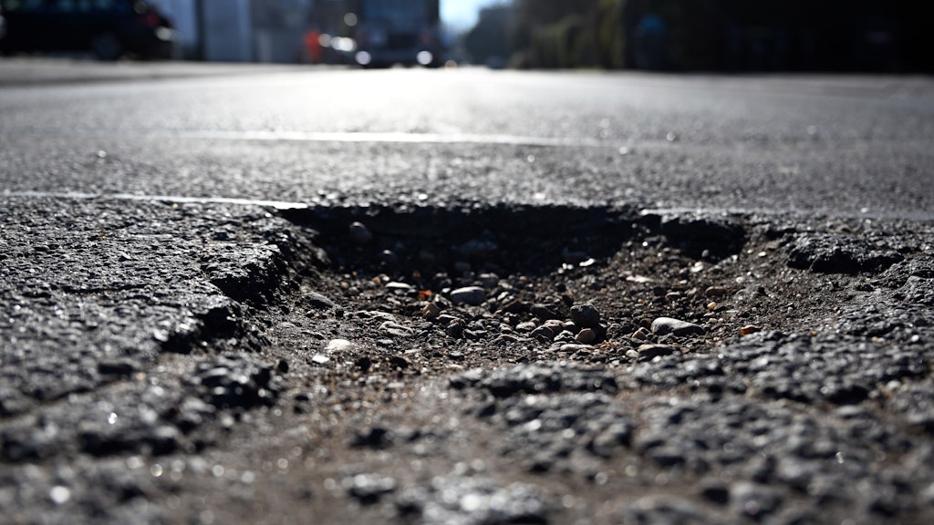 Ein Schlagloch hat sich in einer Straße gebildet. Nach dem Winter ist das ein weit verbreitetes Phänomen.