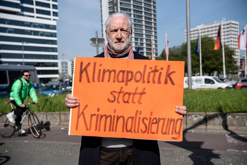 Ein Mann hält am Ernst-Reuter-Platz ein Plakat in den Händen. Aktivisten der Umweltgruppe Letzte Generation hatten eine Straße blockiert. 