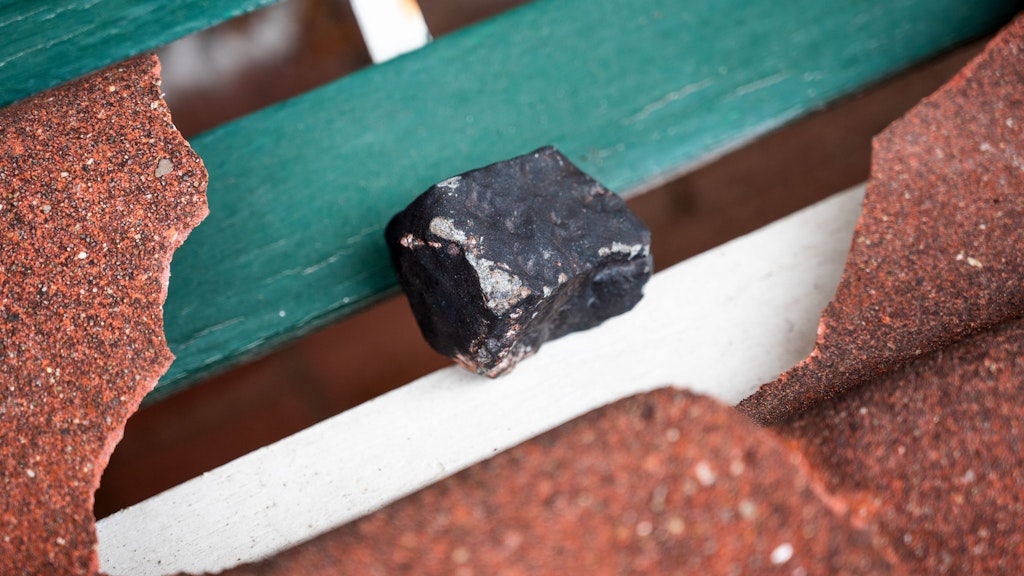 Der niedergegangene Meteorit liegt neben einer zerbrochenen Dachpfanne. Der Gesteinsbrocken von der Größe eines Tennisballs habe das Dach eines Hauses durchschlagen. Dem Deutschen Zentrum für Luft- und Raumfahrt zufolge ist ein solches Ereignis sehr selten. 