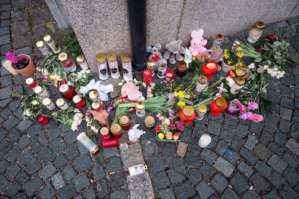 An der Straßenecke zur Zufahrtsstraße zum Kinder- und Jugendhilfezentrum, in dem eine Zehnjährige tot aufgefunden wurde, liegen Blumen, Kuscheltiere und Grablichter auf dem Gehweg.