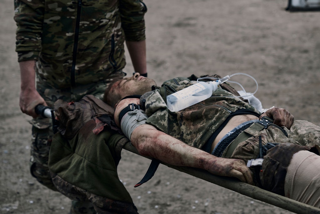 Eine Infusionsflasche auf der Brust, wird ein verwundeter ukrainischer Soldat bei Bachmut in einen „medizinischen Stabilisierungspunkt“ getragen, ein Feldlazarett in einem früheren Verwaltungsgebäude..